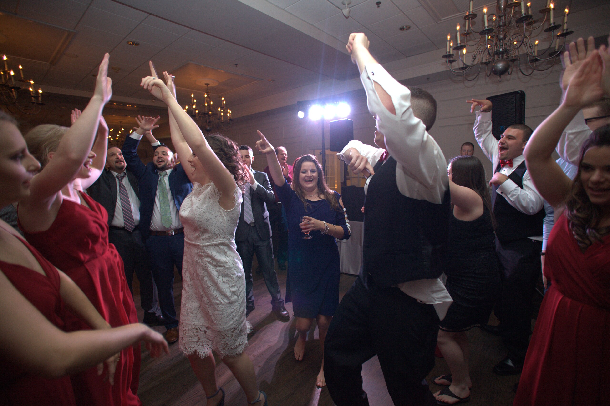 A bride and wedding guests celebrating together on a packed dance floor