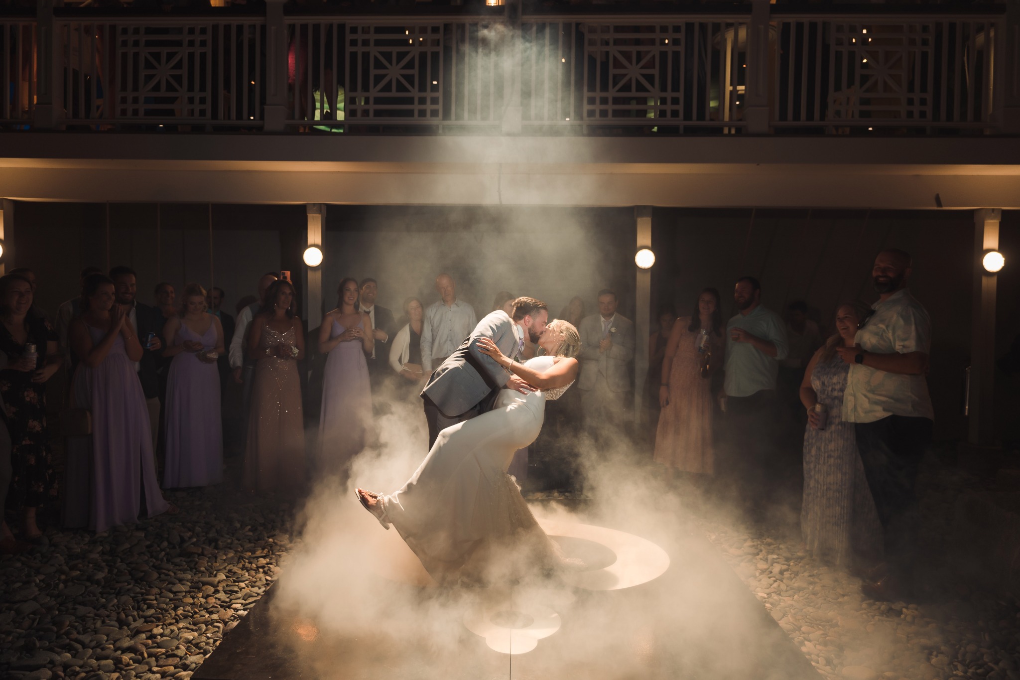 A newlywed couple sharing a dramatic dance-floor moment beneath a spotlight